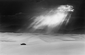 Premium Rates Apply. Dark skies are lit by a shaft of light as a car drives across the desolate White Sands in New Mexico. Original Publication: In black and white book  (Photo by Ernst Haas/Getty Images)